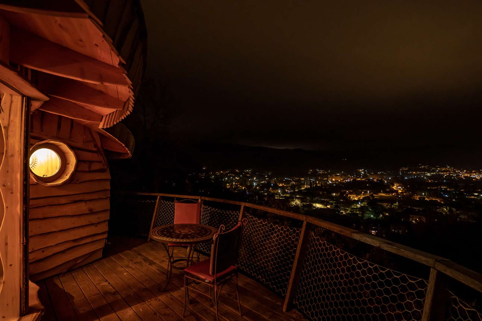Cabane perchée à Languedoc-Roussillon, vue nocturne sur la ville illuminée.