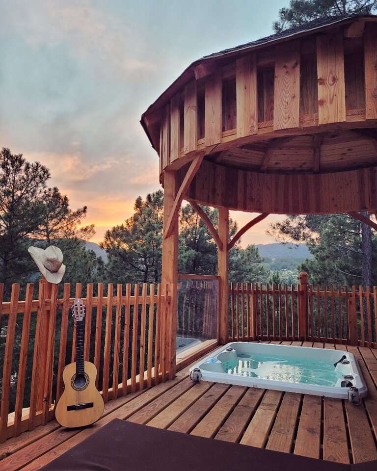 Cassiopee jacuzzi Cabane perchée avec jacuzzi, vue panoramique sur la nature au coucher du soleil.