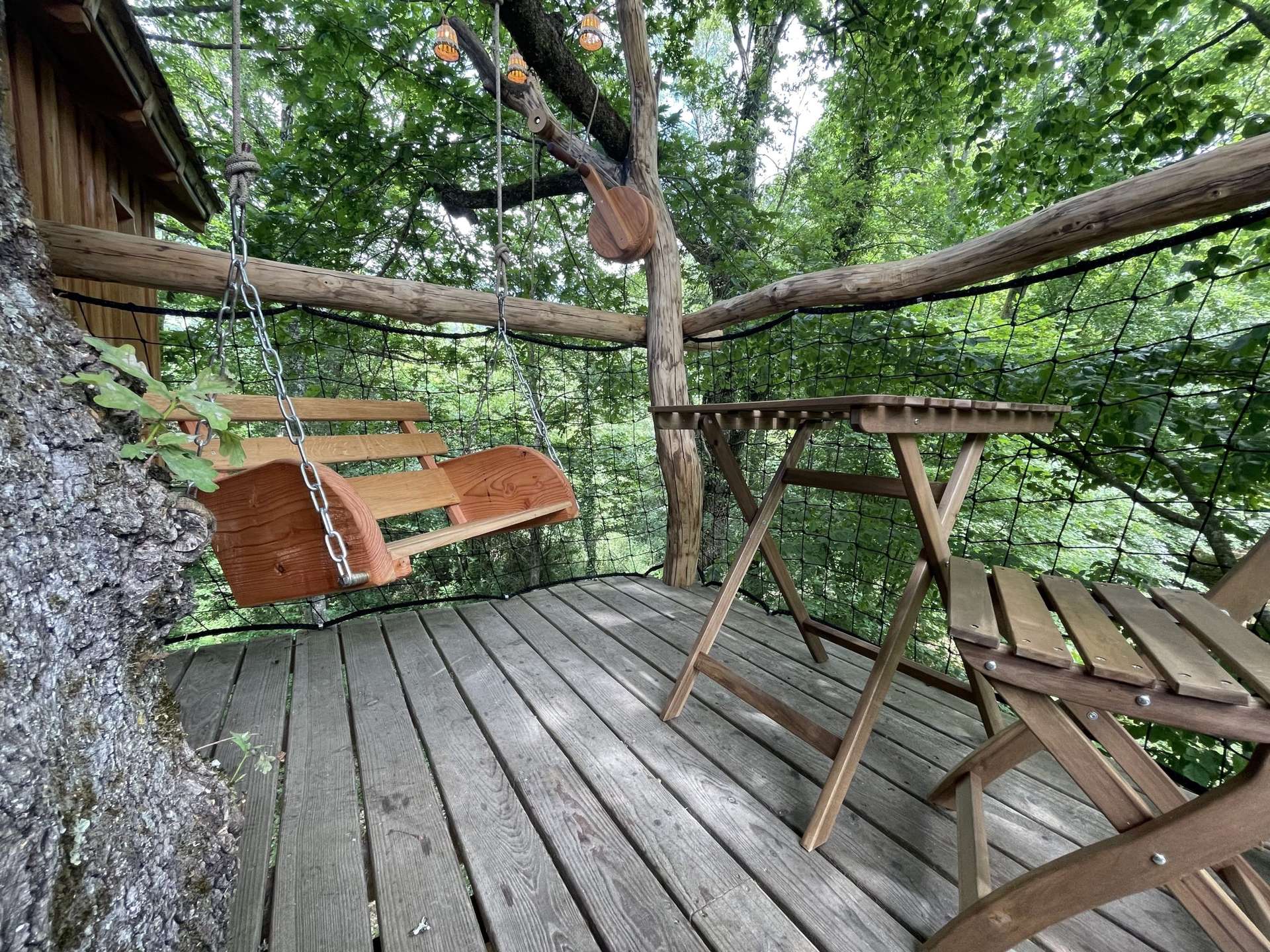 caban'aspe10 crédit aspe.info Cabane perchée en Aquitaine avec balancelle en bois et vue sur la nature environnante.