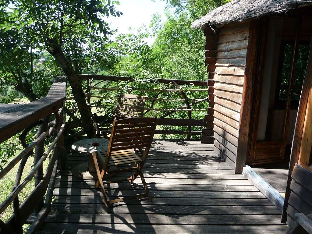 exterieur table Cabane perchée en bois avec terrasse, entourée de verdure à Auvergne-Rhône-Alpes.