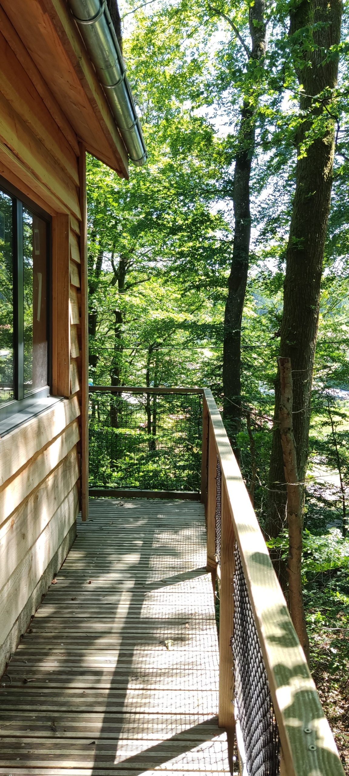 IMG_20210613_144832 Cabane perchée en bois, avec une terrasse donnant sur une forêt verdoyante.
