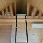 Cabane en bois avec mezzanine, échelle en bois et décoration chaleureuse.