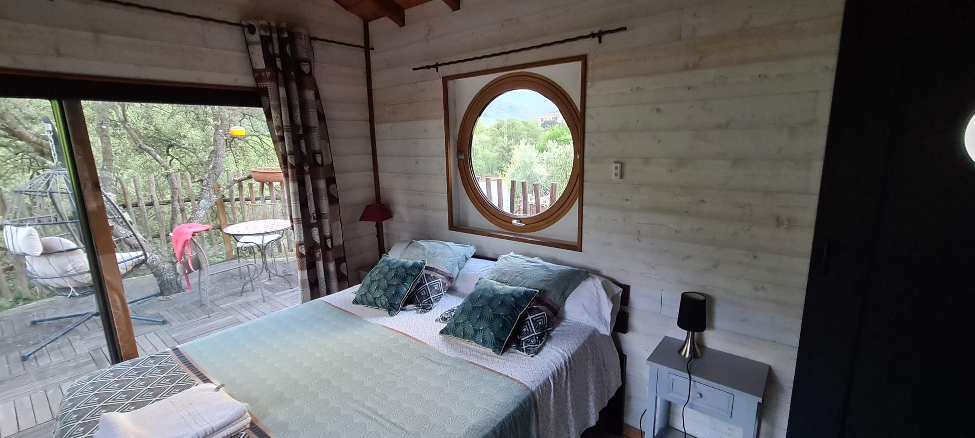 20220828_193049 Chalet en bois avec vue sur la nature, lit double et fenêtre ronde.