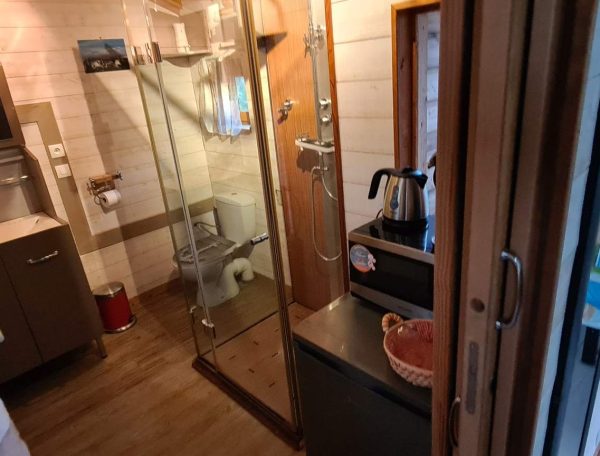 Hébergement insolite en Corse : intérieur moderne avec douche vitrée et lit coloré.