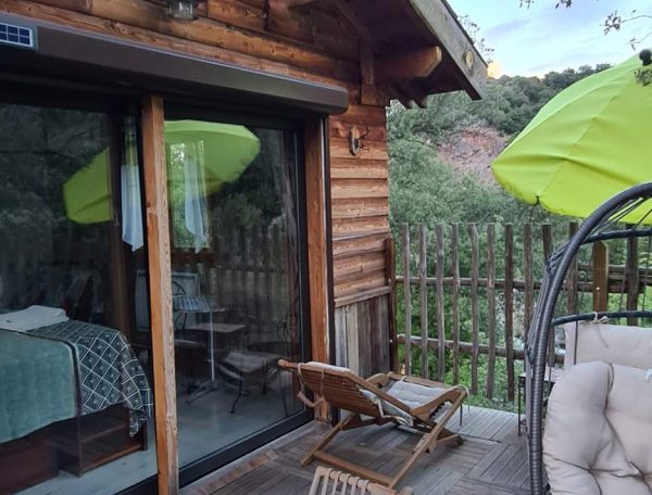 Cabane en bois en Corse avec terrasse ensoleillée et vue sur la nature.