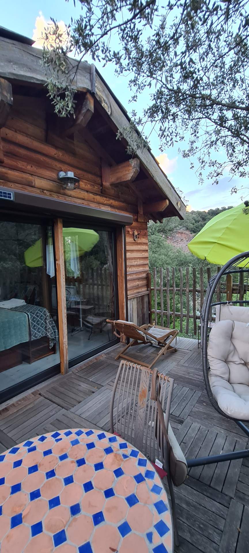 Cabane en bois en Corse avec terrasse ensoleillée et vue sur la nature.