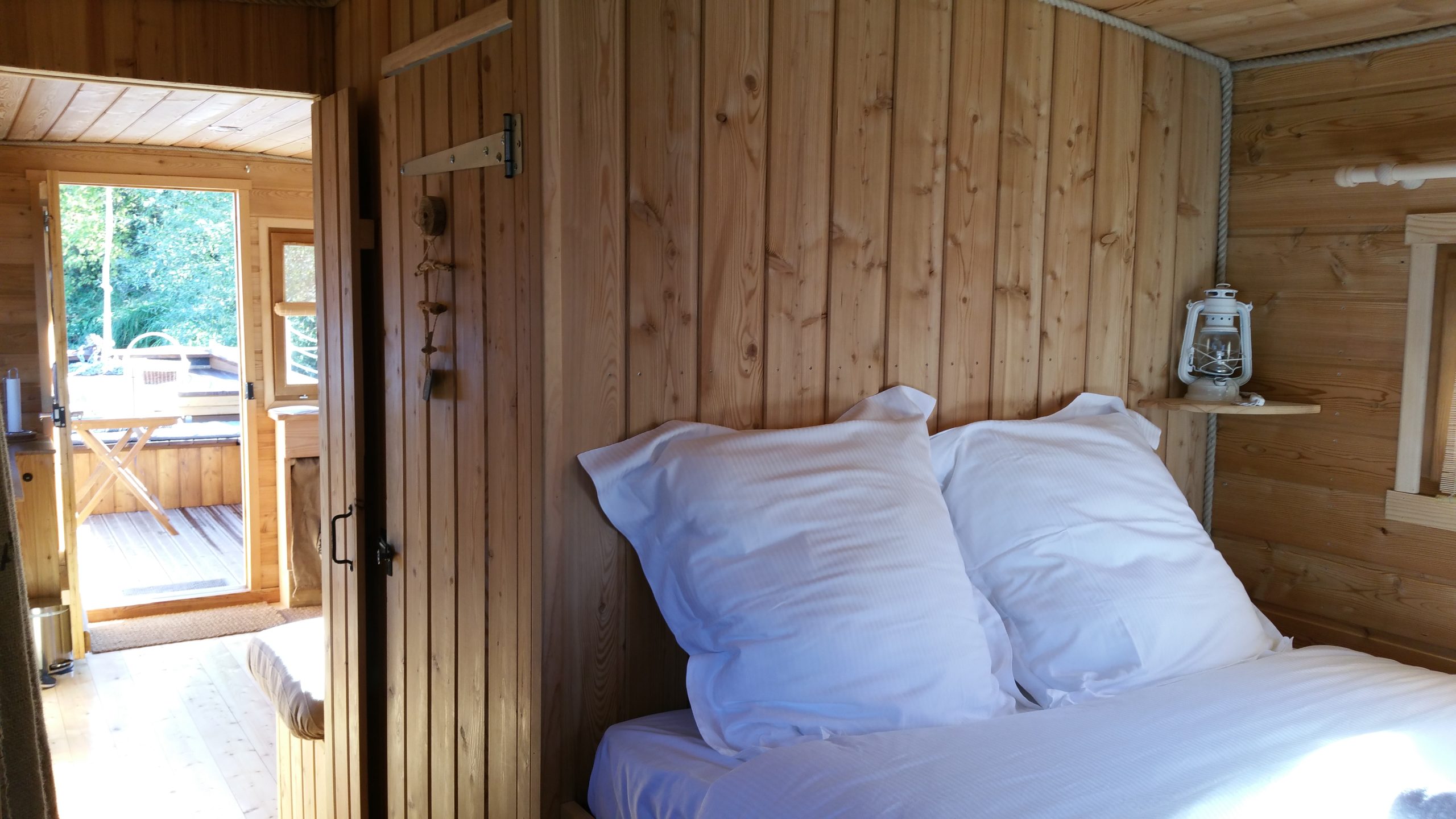 Chambre toue reine Chalet en bois chaleureux avec lit douillet et vue sur la terrasse ensoleillée.