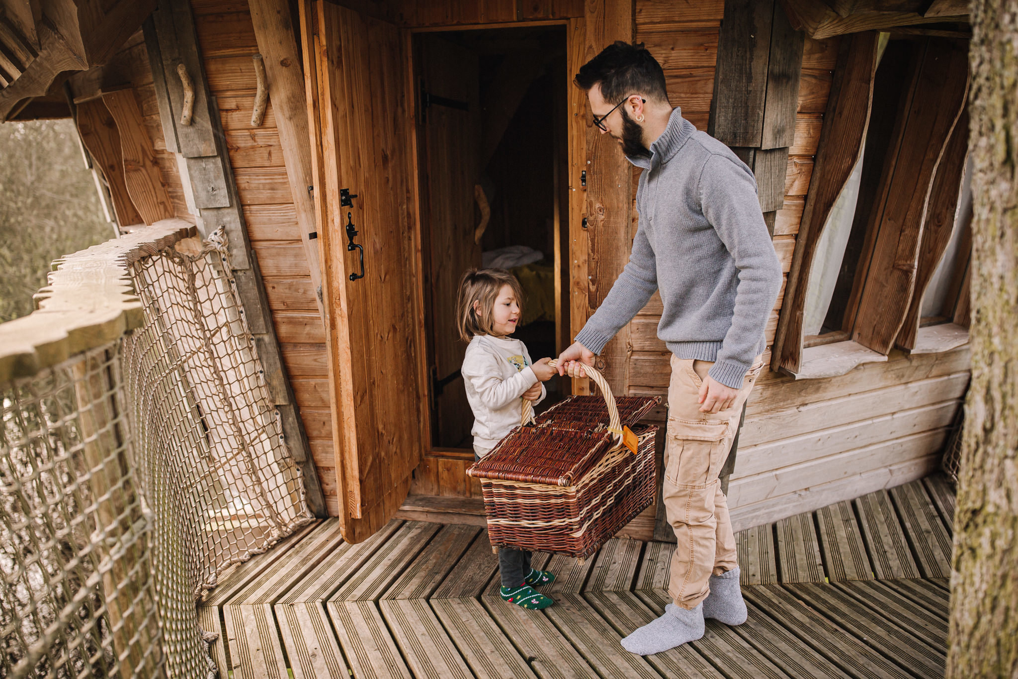 Entreprise_ChouetteCabane_JustineB-147 Cabane perchée dans les arbres, avec un homme et une enfant portant un panier.