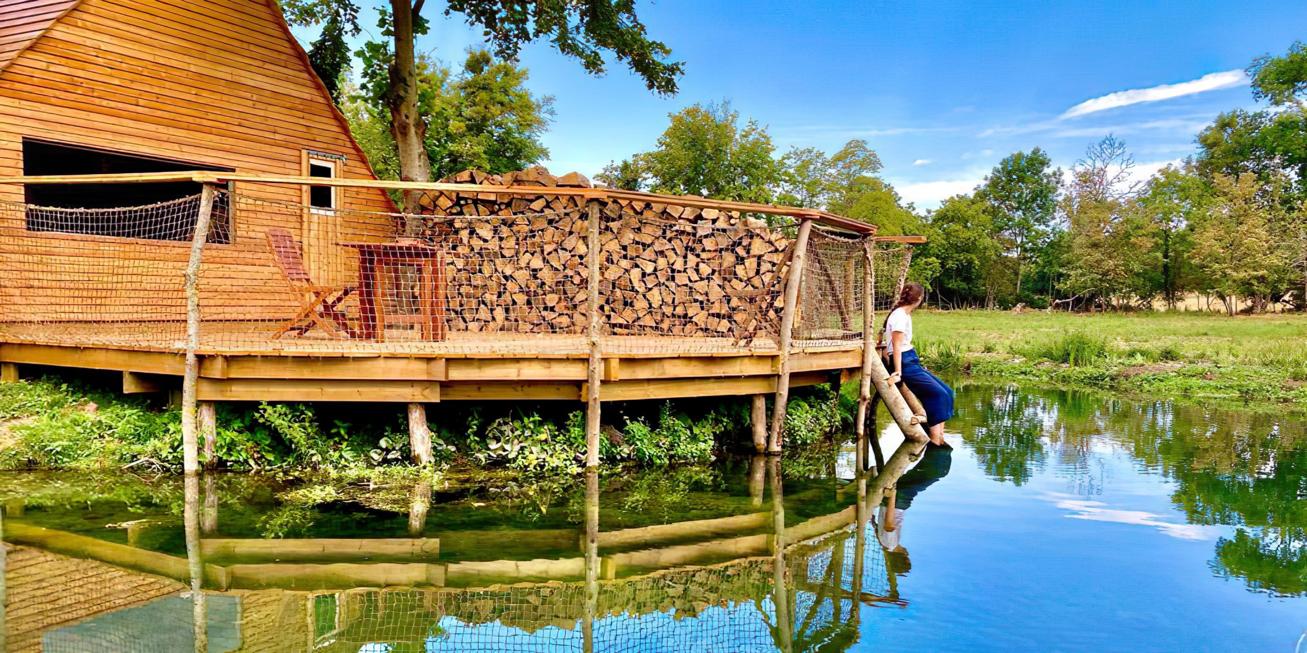P1130902 Cabane sur pilotis en bois, au bord dun étang, entourée de verdure.