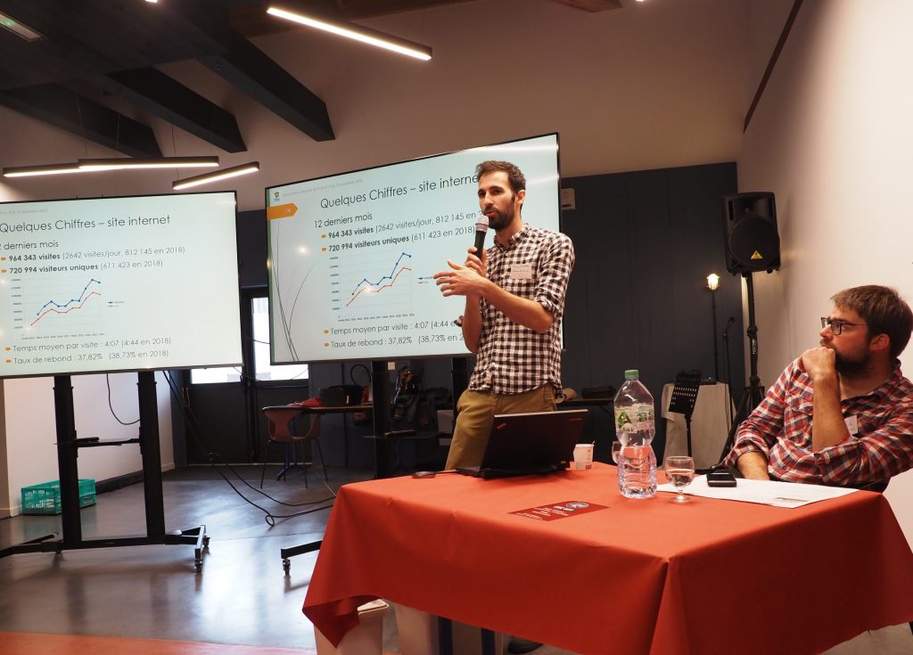 Hébergement touristique en salle de conférence, avec présentateur et écran de projection.