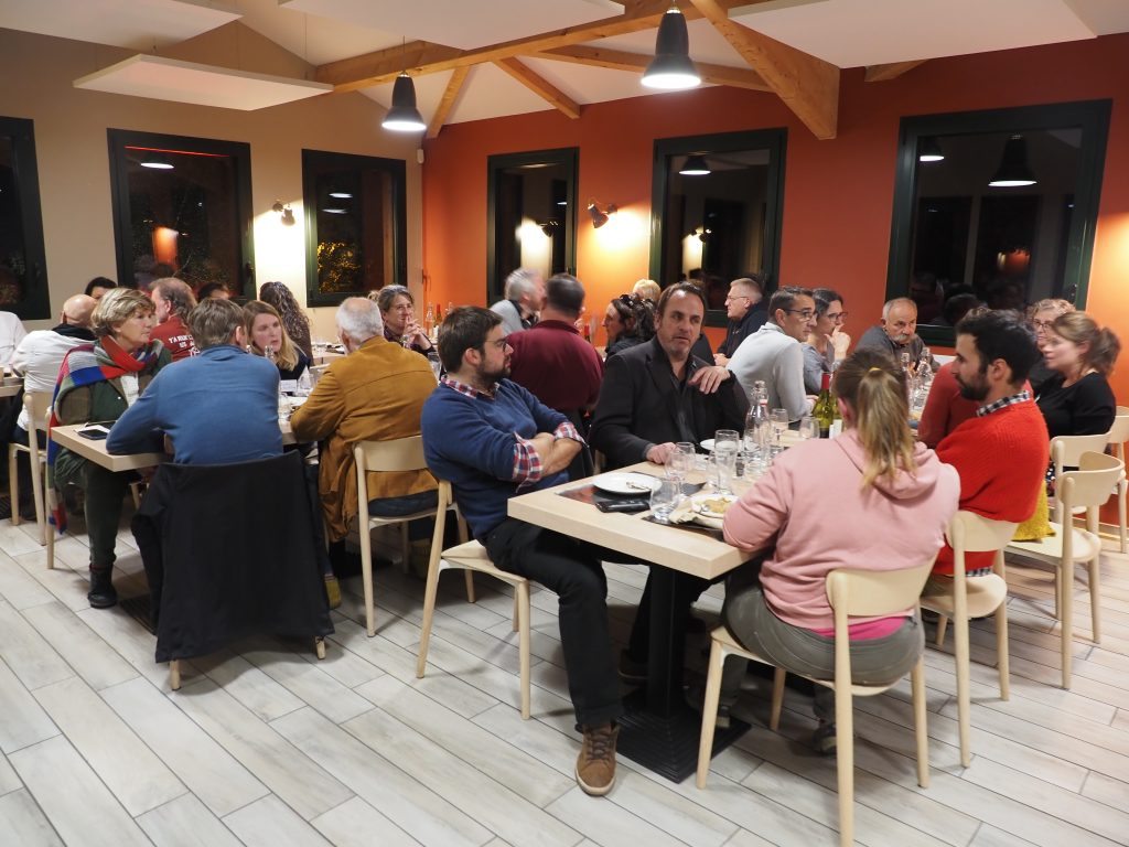 Salle à manger conviviale dun gîte, avec des convives autour de tables en bois.