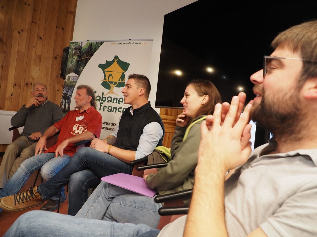 Groupe de personnes en discussion dans un hébergement chaleureux en bois.