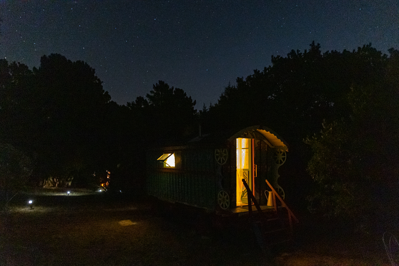 065A1394 Roulotte colorée sous les étoiles, éclairée par une douce lumière nocturne.