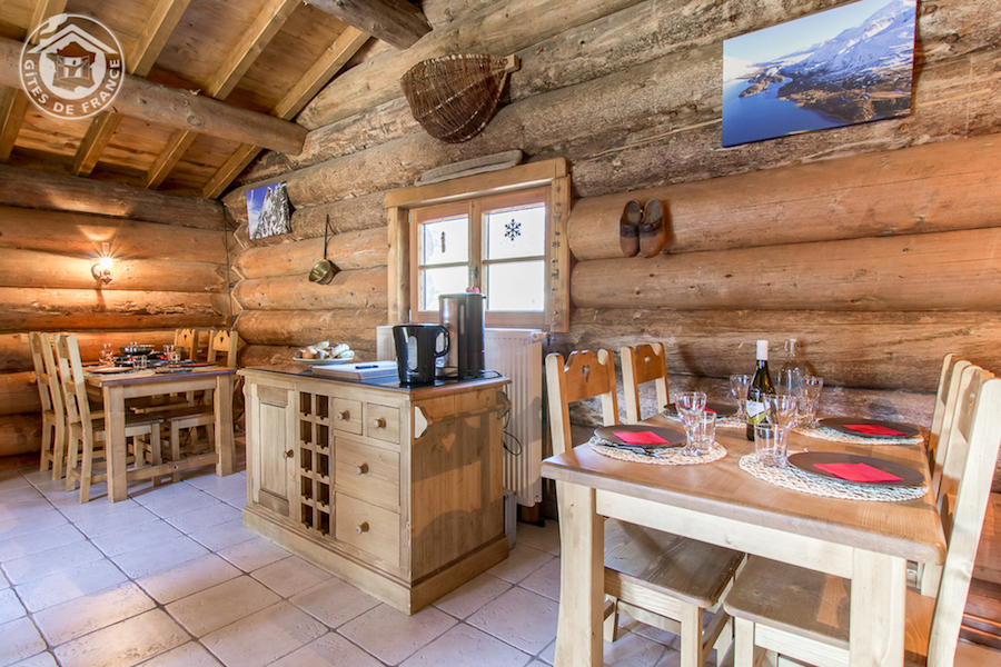 17 La Table D'Hôtes 2 (Chalet Commun) Chalet en bois chaleureux en Auvergne-Rhône-Alpes, avec tables en bois et vue montagne.