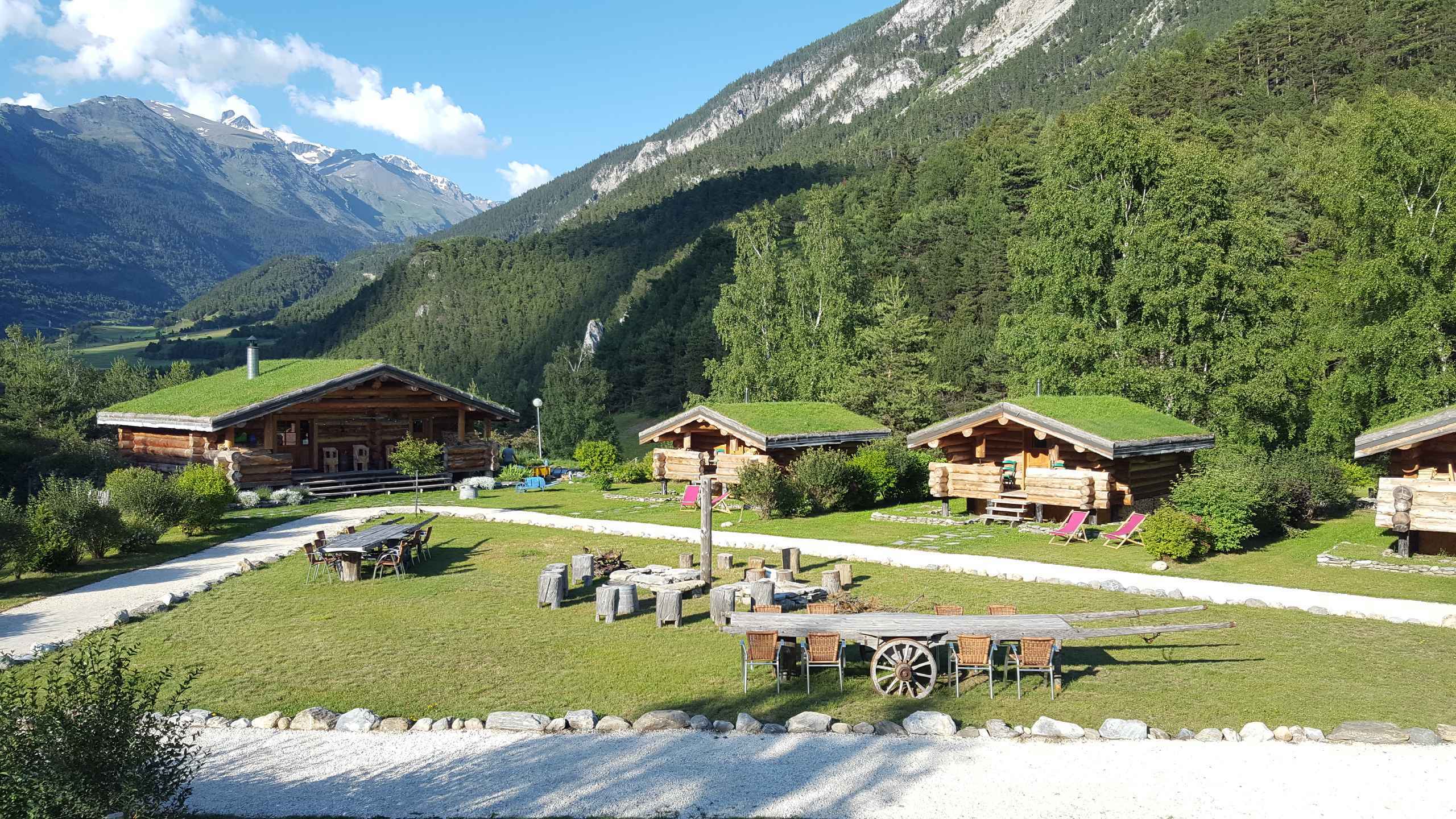 3 feu de camp printemps Chalets en bois avec toits végétalisés, entourés de verdure en Auvergne-Rhône-Alpes.