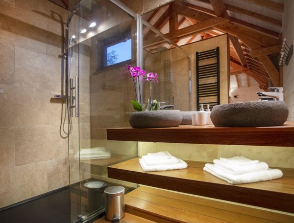 Salle de bain moderne dun hébergement insolite en Languedoc-Roussillon, avec fleurs et bois.