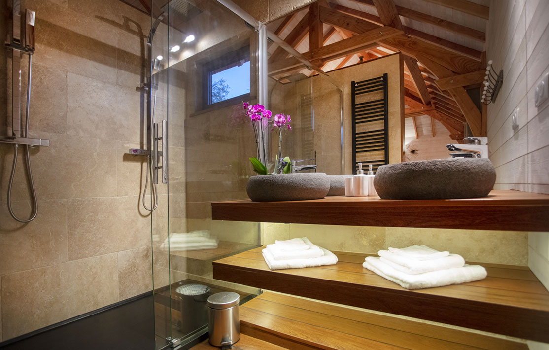 Salle de bain moderne dun hébergement insolite en Languedoc-Roussillon, avec fleurs et bois.