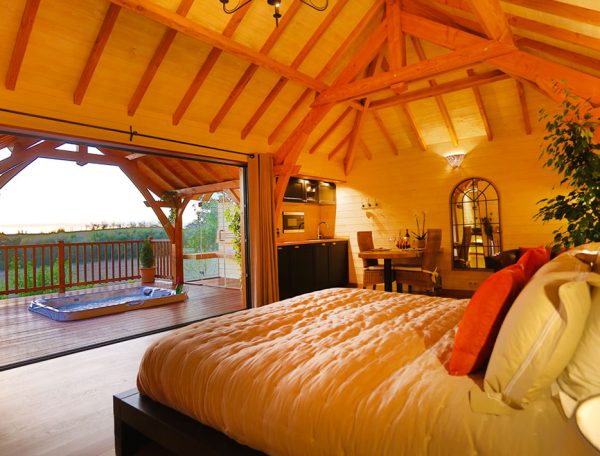 Chalet en bois avec vue panoramique, lit douillet et terrasse ensoleillée.