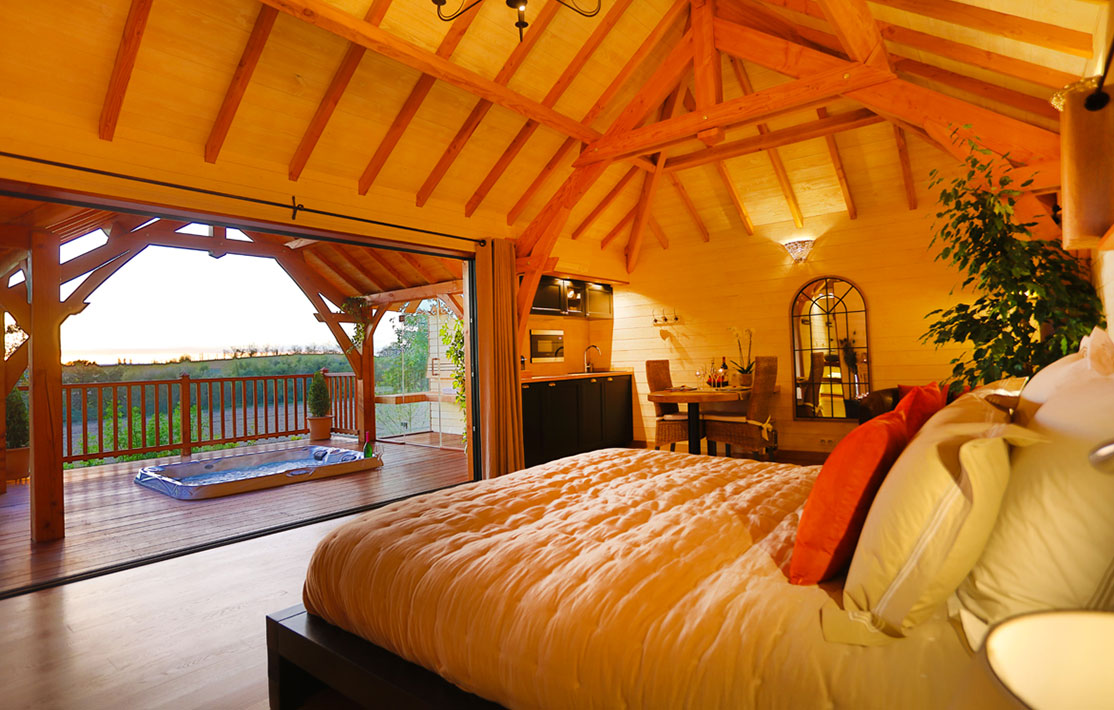 Chalet en bois avec vue panoramique, lit douillet et terrasse ensoleillée.