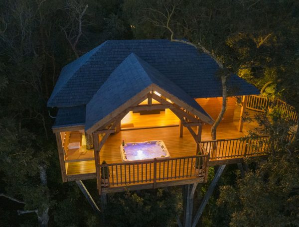 Cabane perchée dans les arbres avec jacuzzi sur la terrasse, au cœur de la nature.