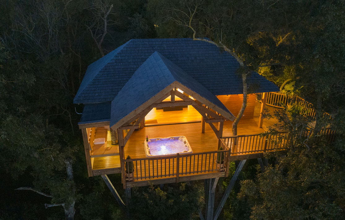 Cabane perchée dans les arbres avec jacuzzi sur la terrasse, au cœur de la nature.