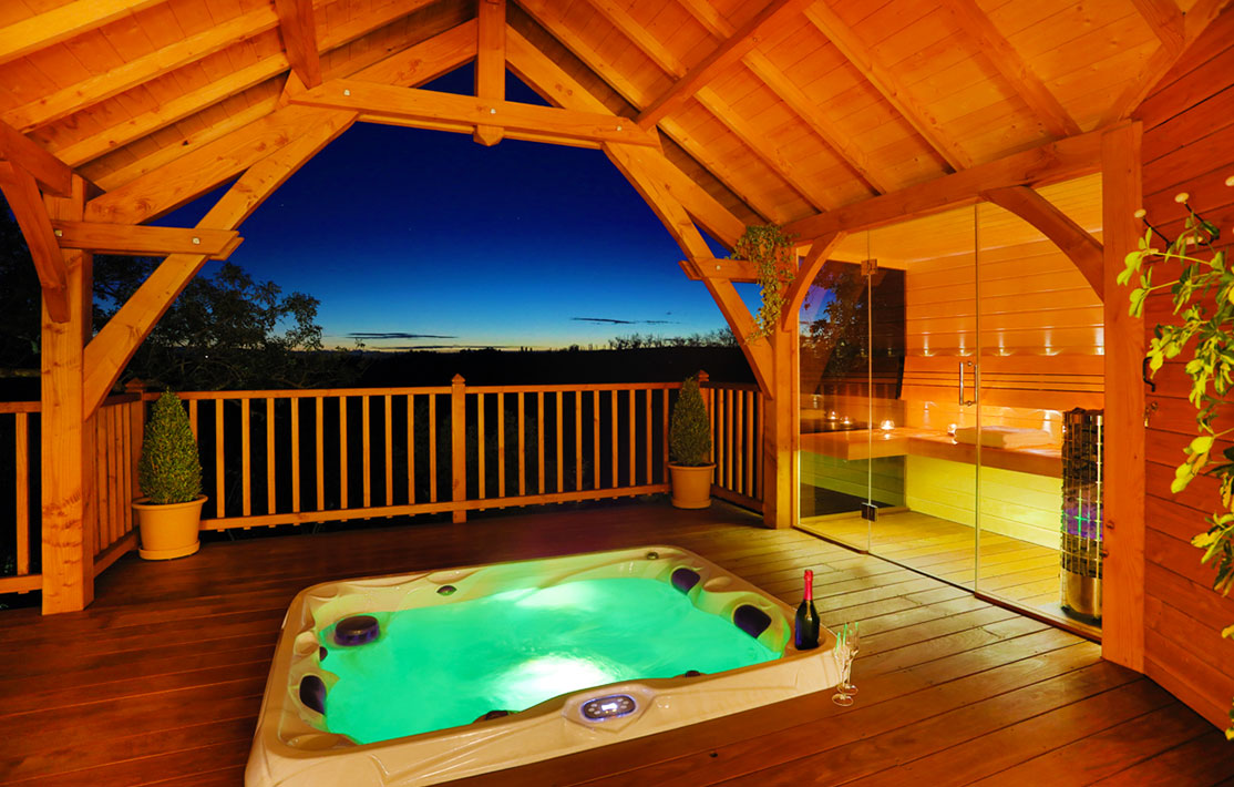 Cabane en bois avec jacuzzi, offrant une vue imprenable sur le coucher de soleil.