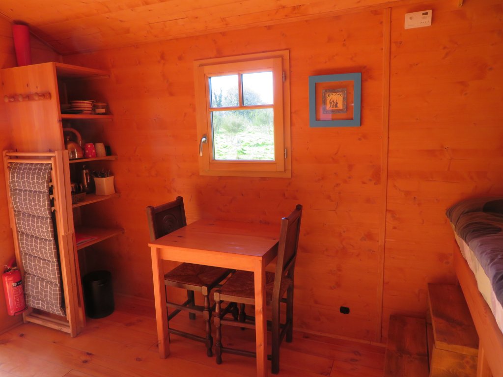 IMG_6531 Intérieur chaleureux dun hébergement insolite en Bretagne, avec table en bois et fenêtre.