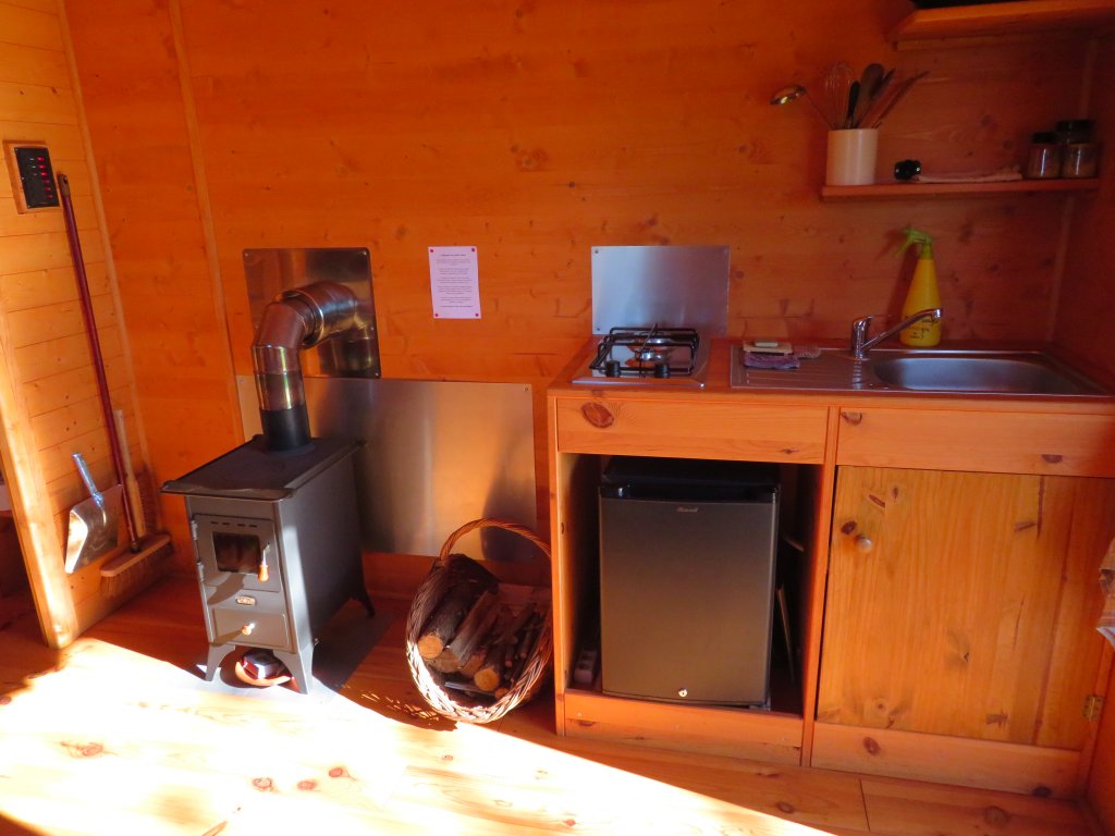 IMG_6535 Intérieur chaleureux dun chalet en bois en Bretagne, avec poêle à bois et cuisine équipée.
