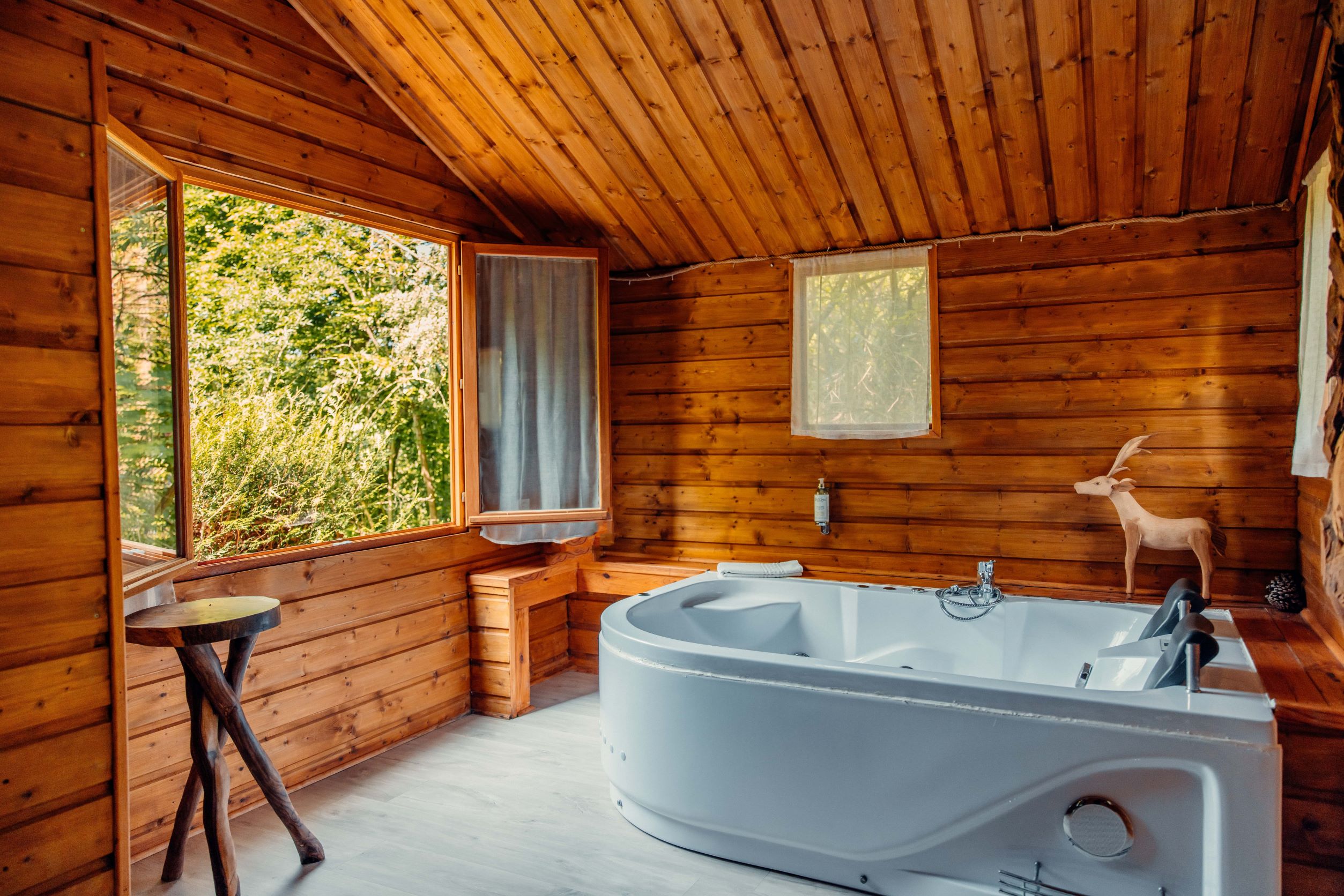 Passage secret balnéothérapie Bois de Rosoy crédit - Elsa et Cyril Mai 2022-min Cabane en bois avec baignoire, grandes fenêtres offrant une vue sur la nature.