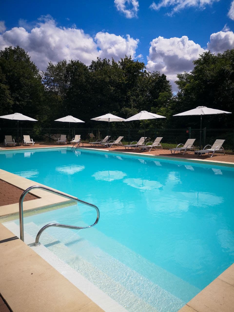 piscine bois de rosoy crédit HPA FOREST 2021 Hébergement insolite en Hauts-de-France avec piscine turquoise et chaises longues sous parasols.