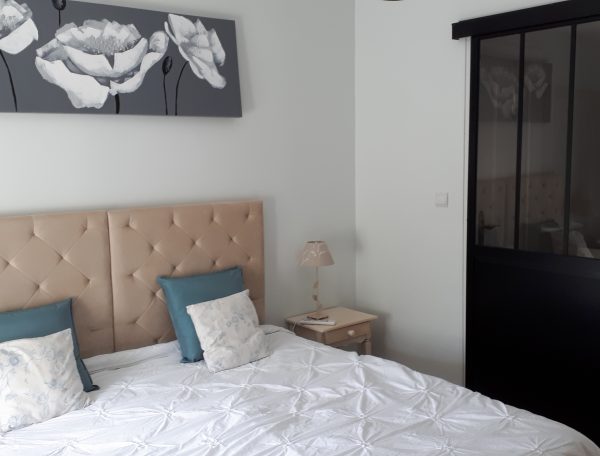 Chambre dhôtes moderne avec lit douillet et décoration florale apaisante.