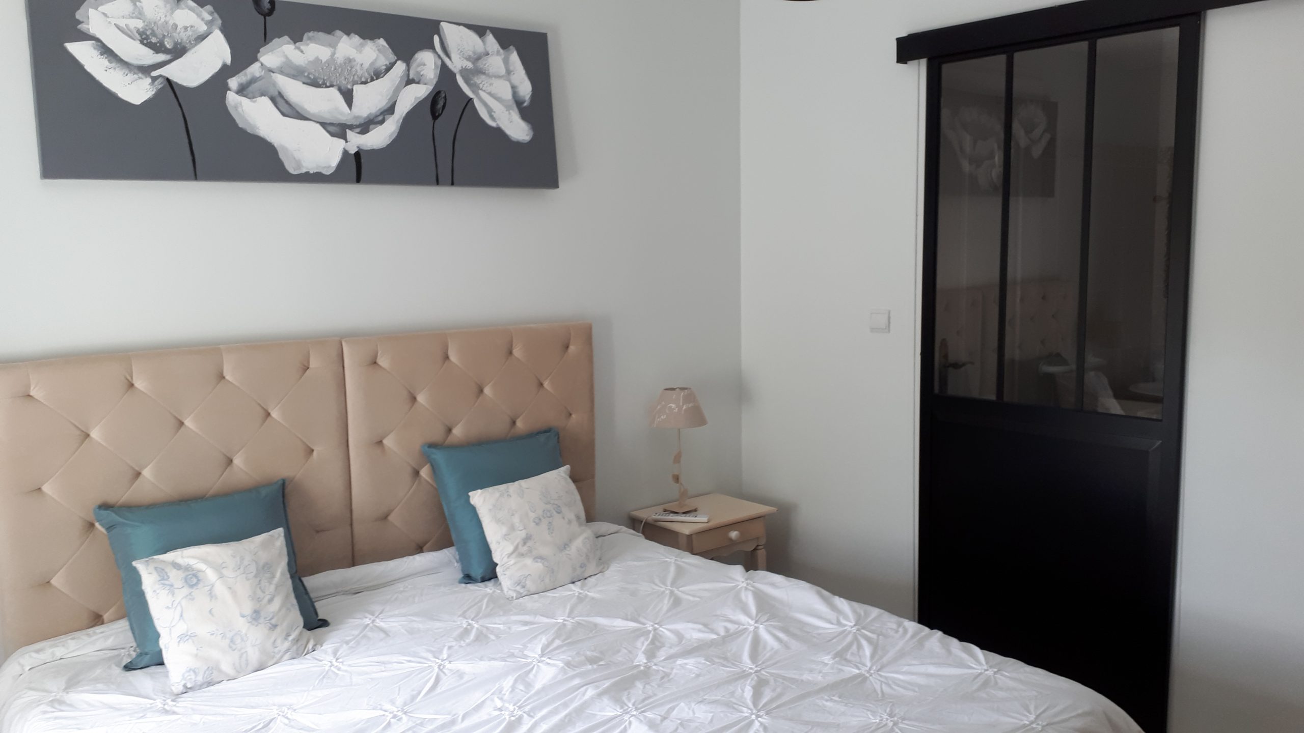 Chambre dhôtes moderne avec lit douillet et décoration florale apaisante.