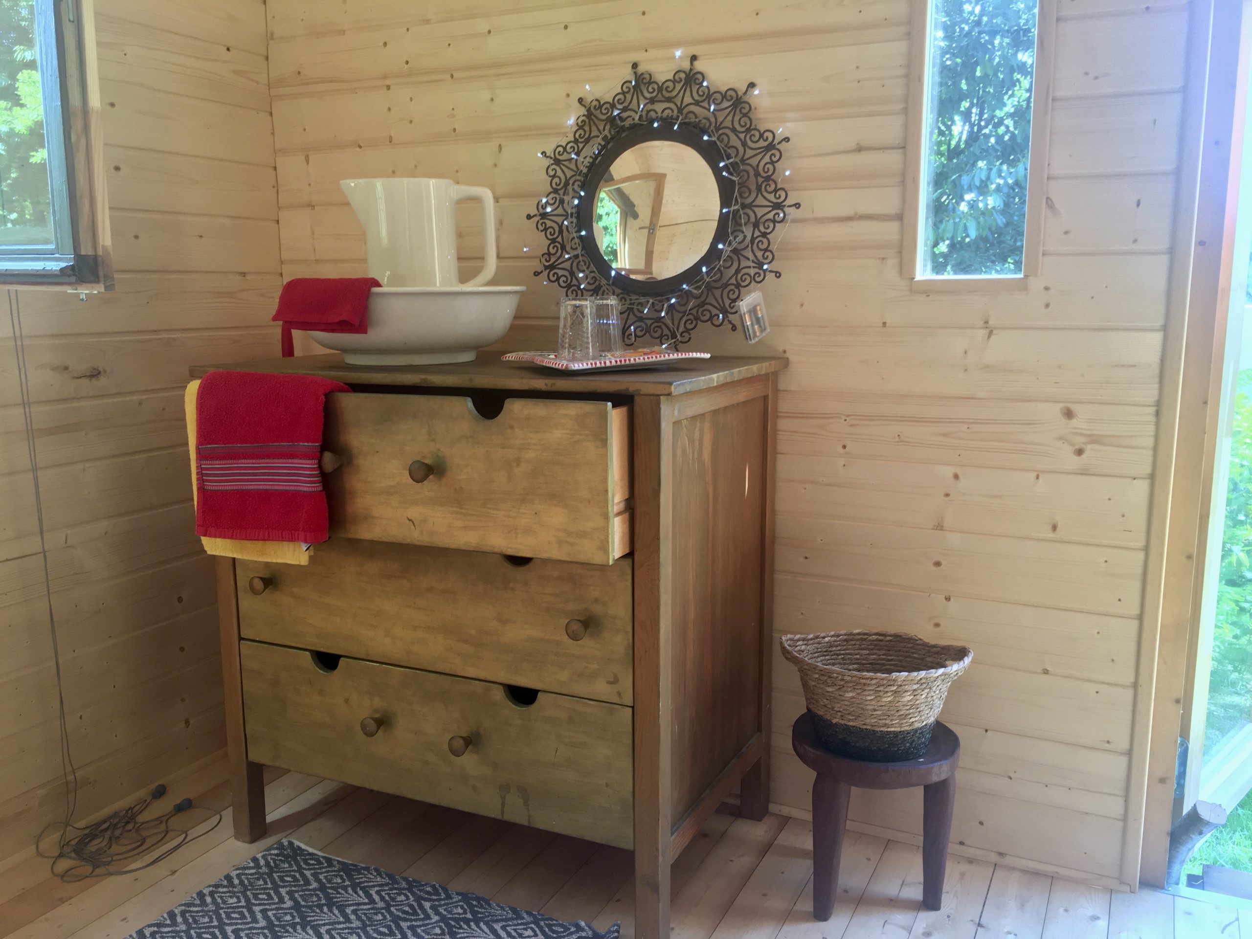 8A53837D-70EA-4743-AD3D-E55D40CBE0EE_1_201_a Hébergement insolite en Basse-Normandie : intérieur en bois avec meuble vintage et miroir décoratif.