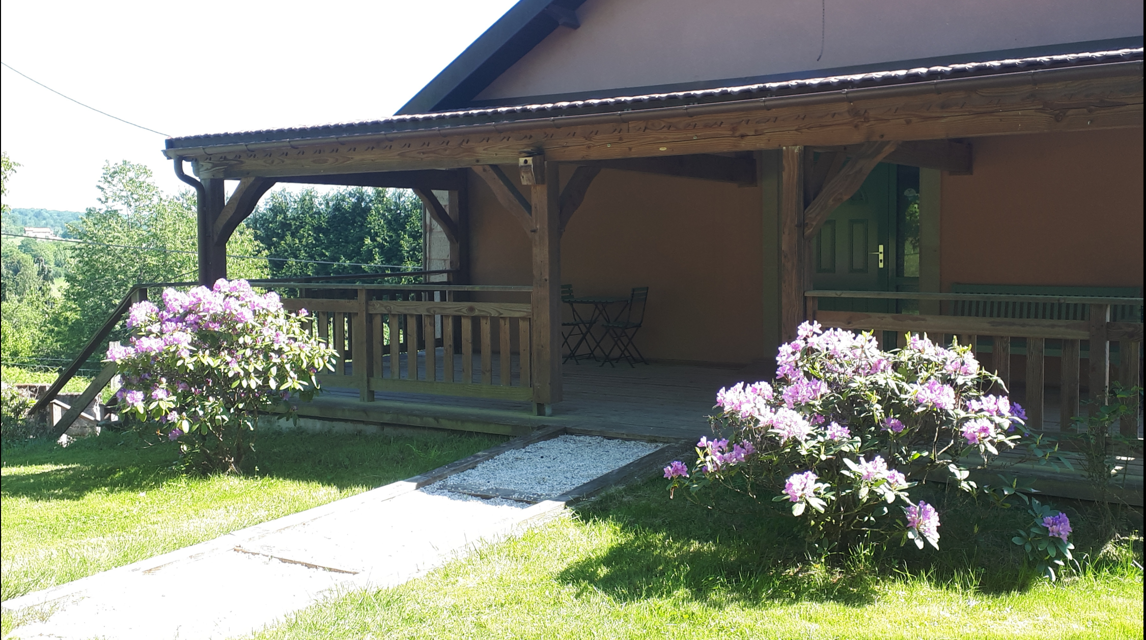 Hébergement insolite en bois avec terrasse, entouré de fleurs colorées à Grand-Est.