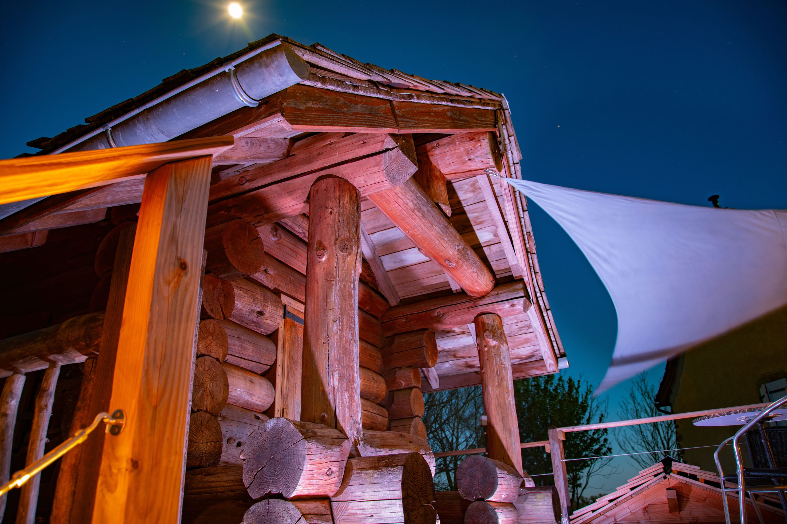 Cabane en bois dans les Midi-Pyrénées, illuminée sous la lune.
