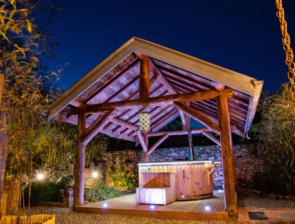 Hébergement insolite en Midi-Pyrénées, avec un spa sous un abri en bois illuminé.