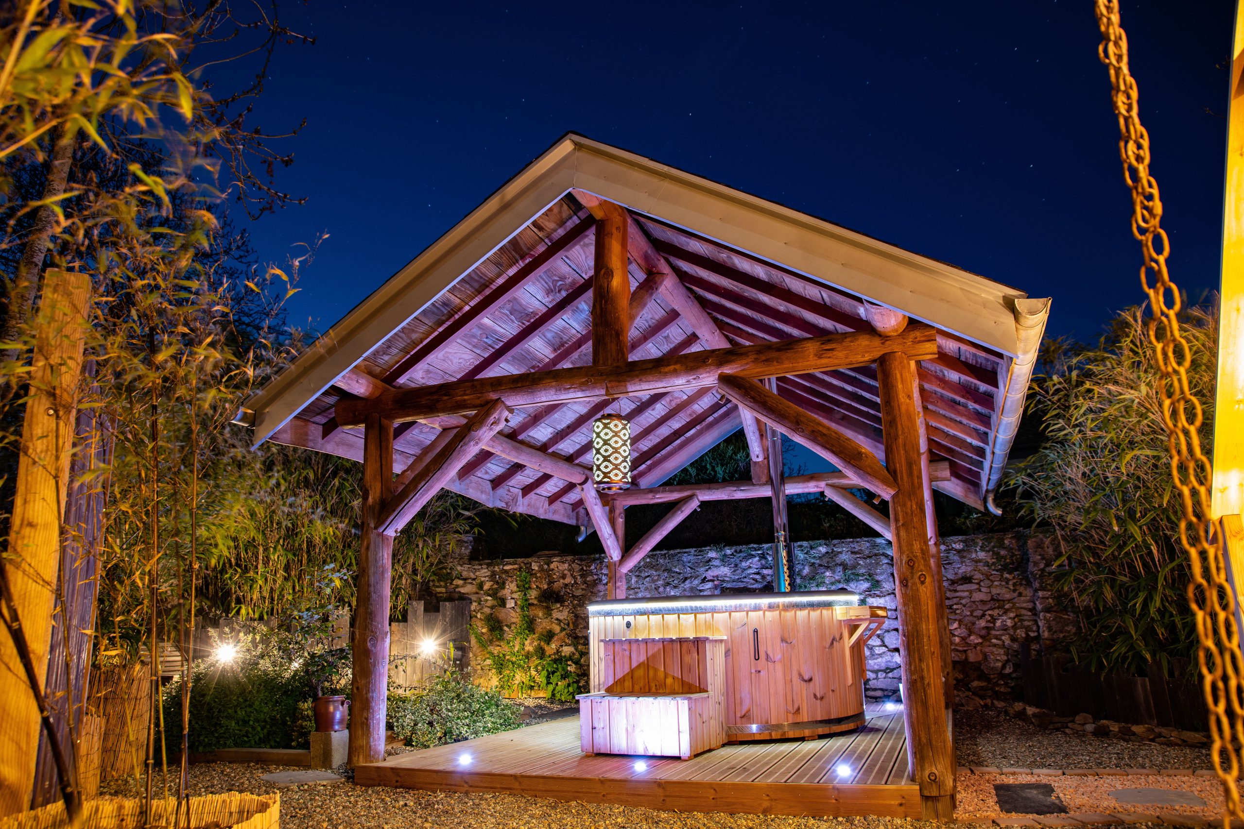 Hébergement insolite en Midi-Pyrénées, avec un spa sous un abri en bois illuminé.