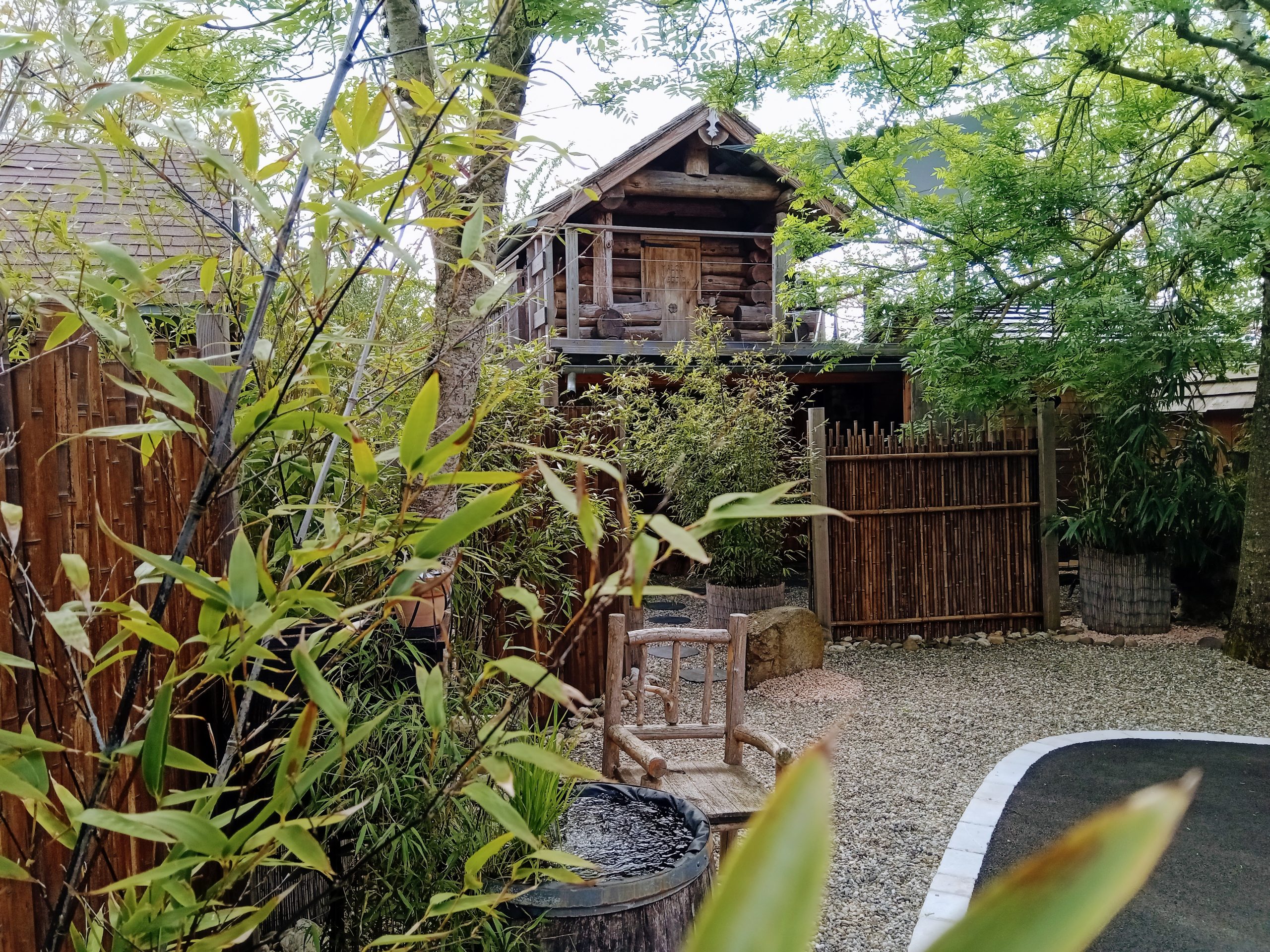 Cabane en bois perchée, entourée de verdure et dun jardin zen apaisant.