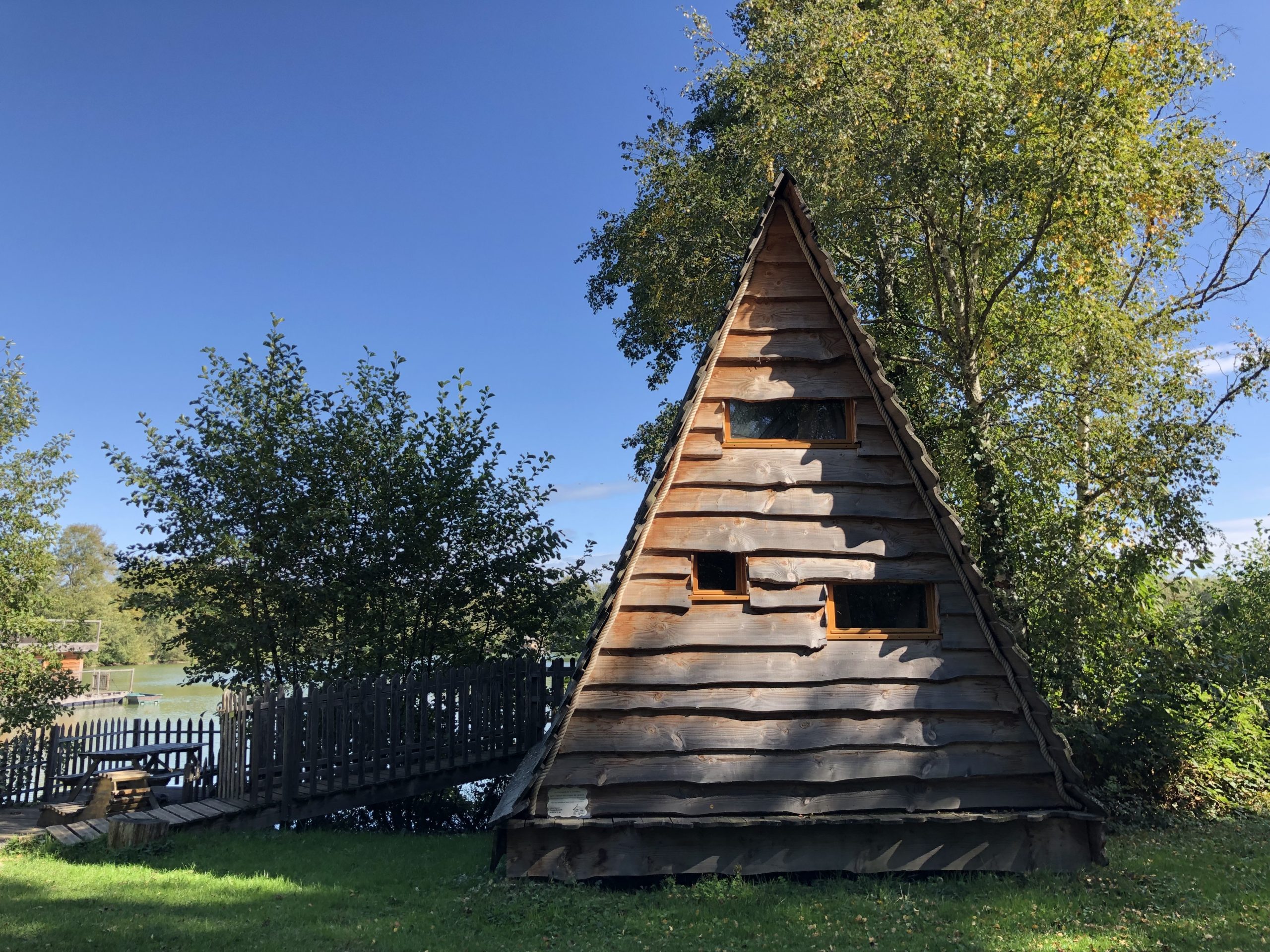 IMG_9123 Cabane en bois en forme de pyramide, entourée darbres verdoyants à Auvergne-Rhône-Alpes.