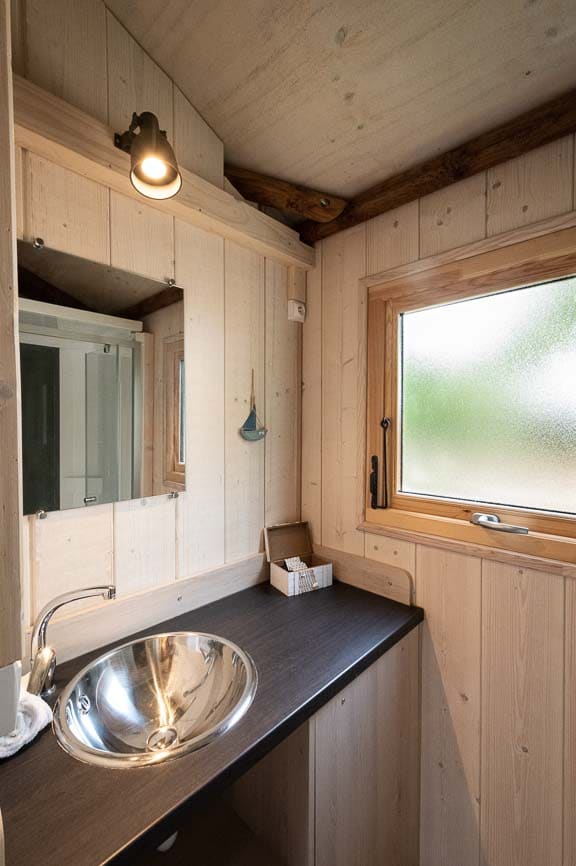 cabanetrappeur10 Hébergement insolite en bois à Champagne-Ardennes avec lavabo design et lumière chaleureuse.