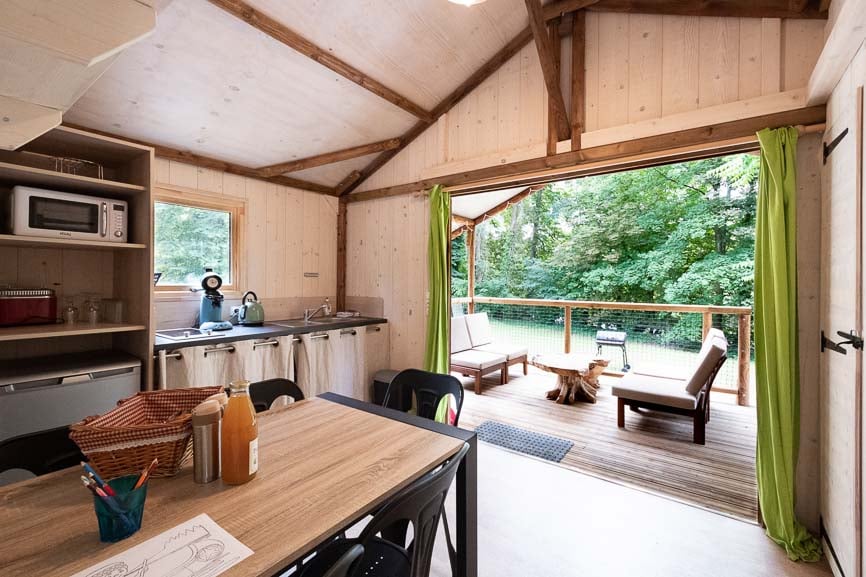 cabanetrappeur7 Cabane en bois à Champagne-Ardennes avec terrasse et vue sur la forêt verdoyante.