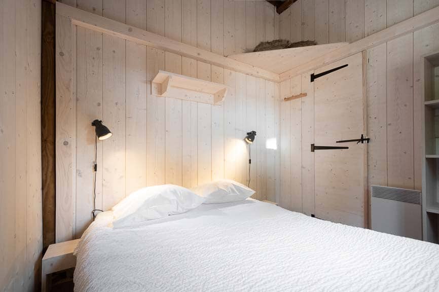 cabanetrappeur9 Chalet en bois à Champagne-Ardennes, avec un lit douillet et des murs clairs.