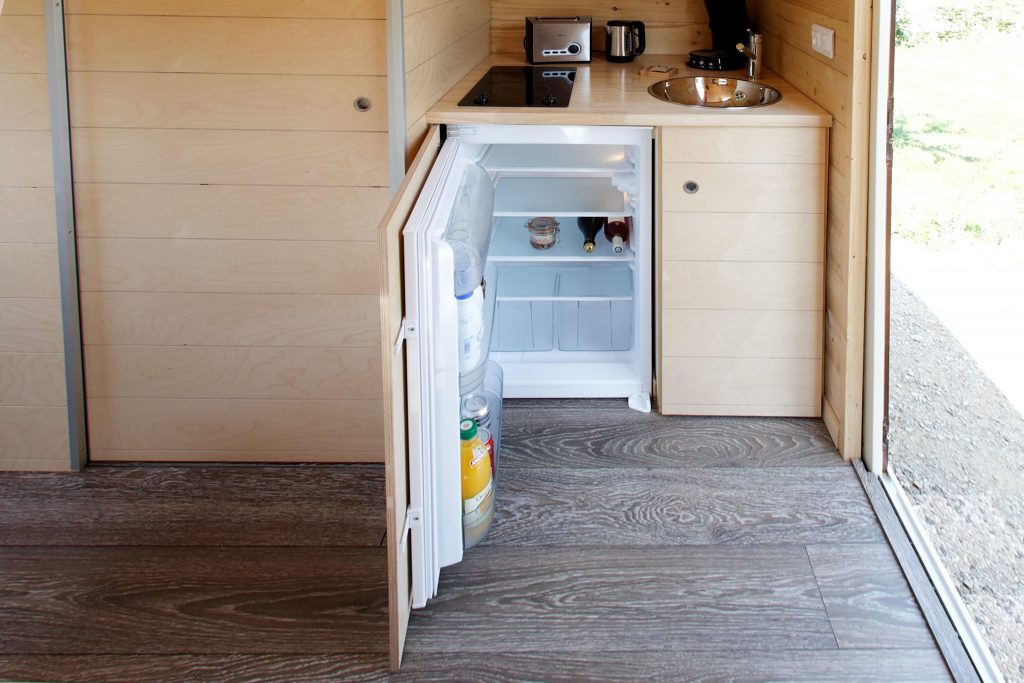carre-etoile5 Intérieur dun hébergement insolite en bois avec kitchenette et réfrigérateur.