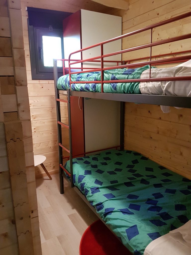 gretel10 Chambre en bois avec lits superposés, décor coloré et ambiance chaleureuse.