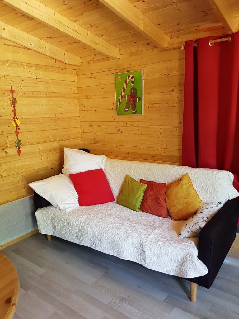 gretel11 Cabane en bois à Champagne-Ardennes, avec un canapé coloré et des coussins décoratifs.