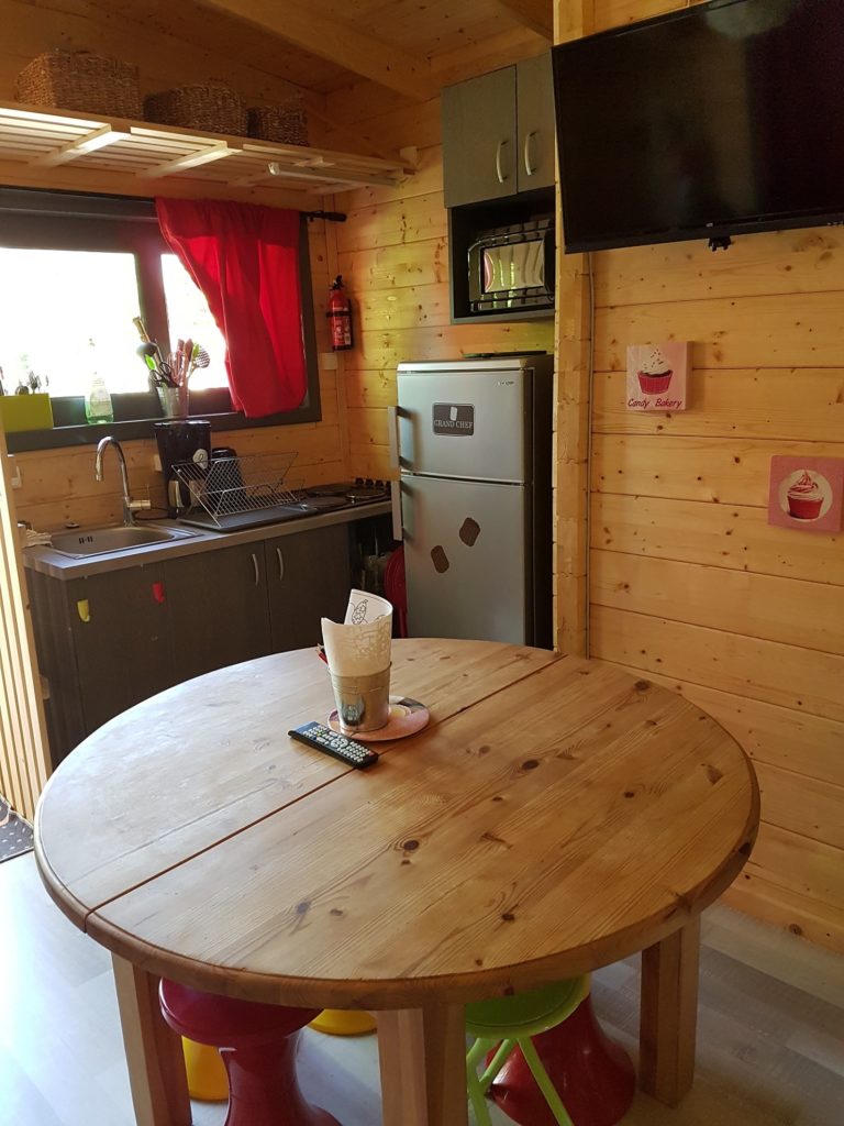 gretel4 Chalet en bois à Champagne-Ardennes avec cuisine équipée et table ronde colorée.