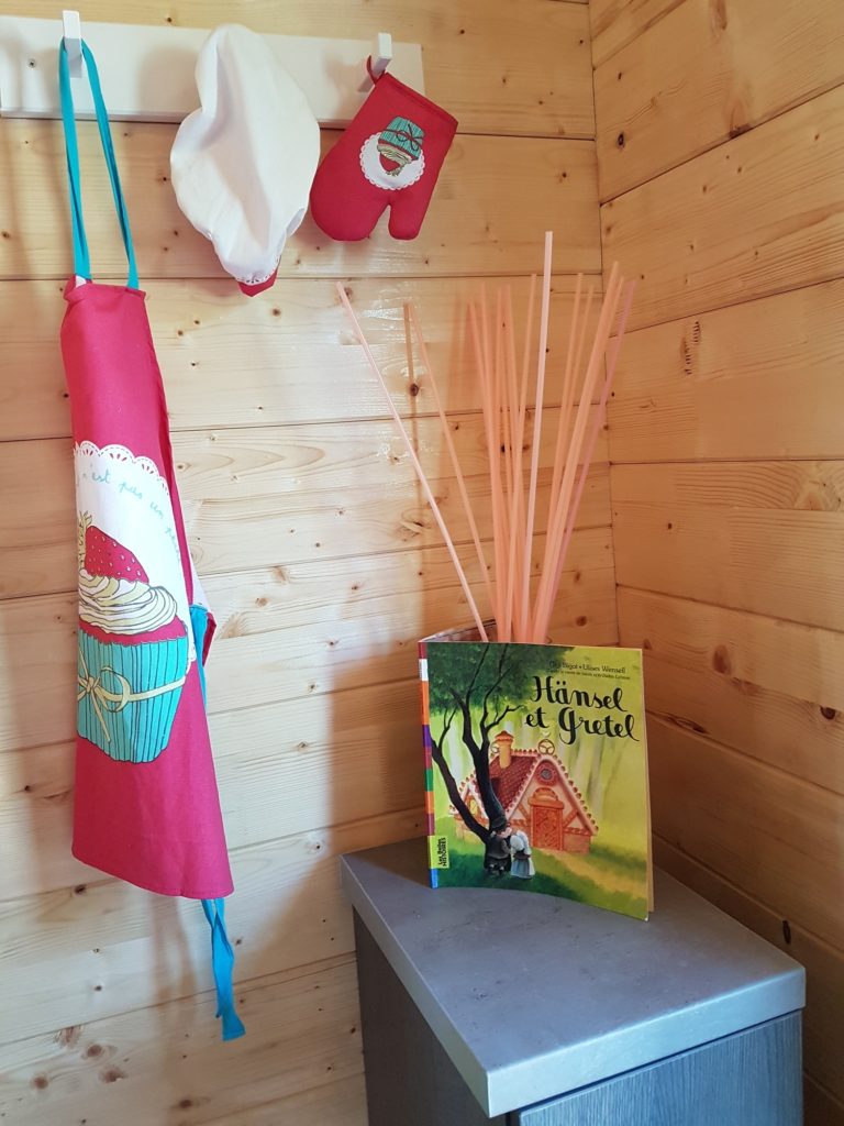 gretel7 Cabane en bois à Champagne-Ardenne, décor cosy avec livre et accessoires de cuisine.