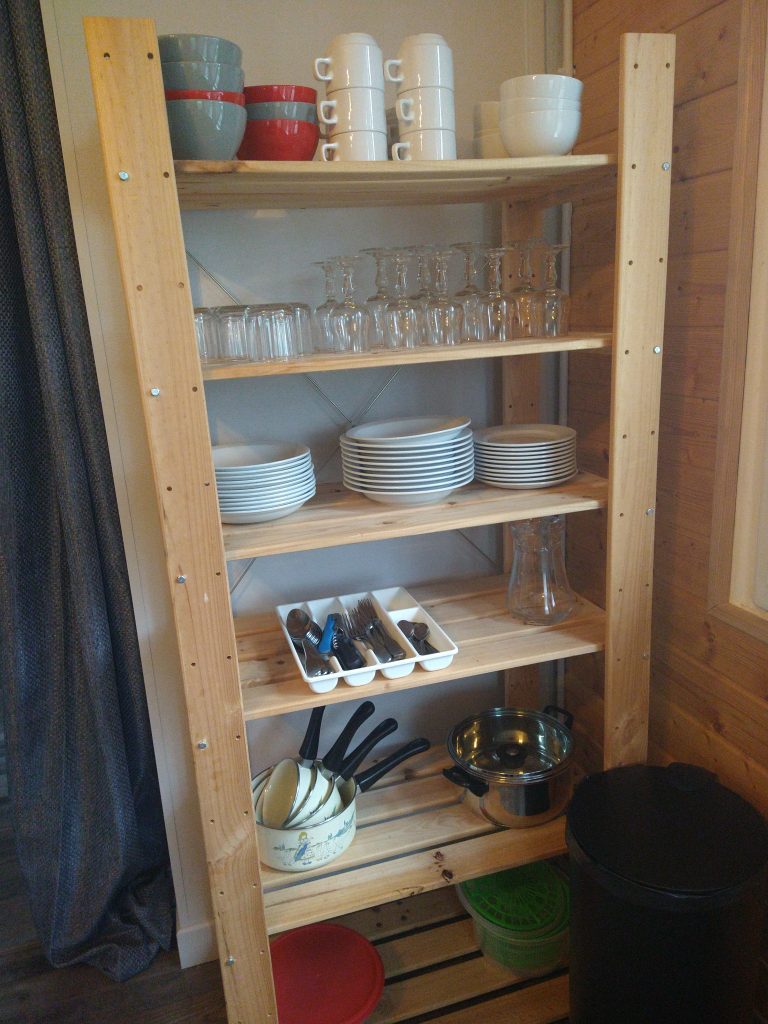 ratatouille10 Étagère en bois dans un hébergement insolite, avec vaisselle colorée et ustensiles de cuisine.