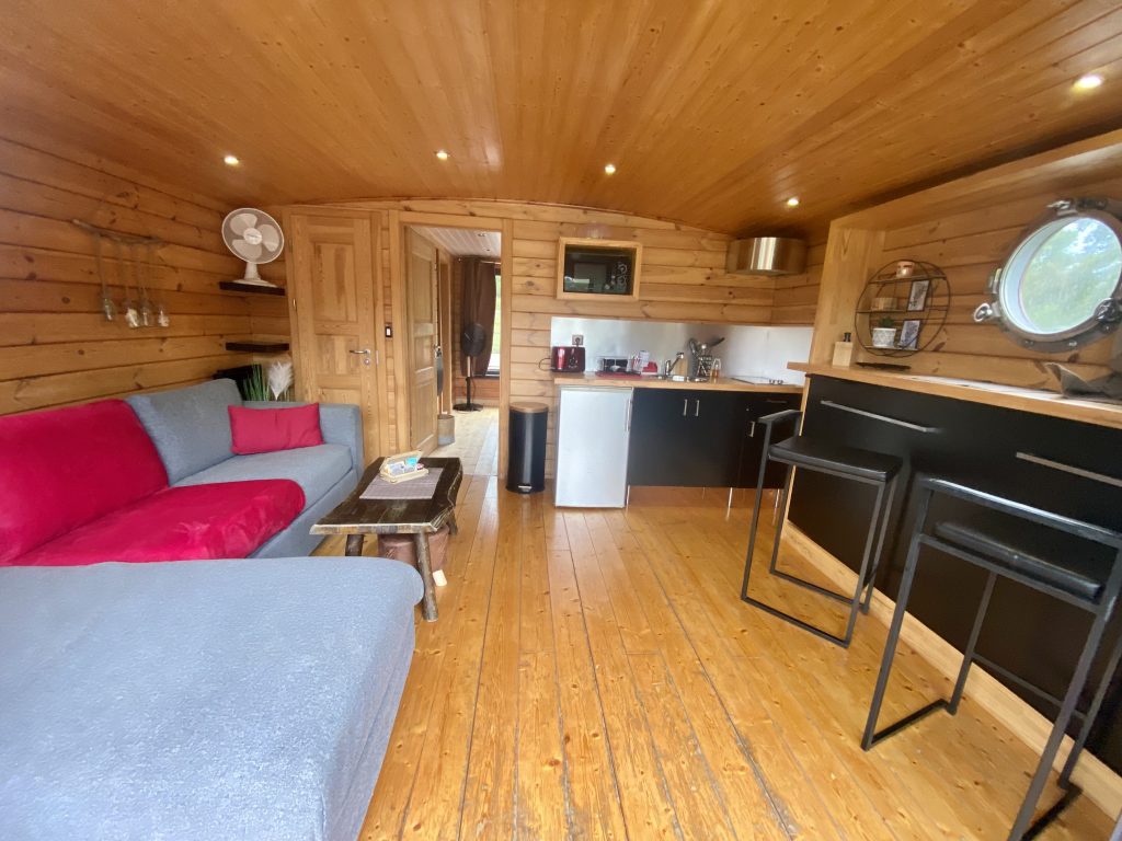 touespa7 Hébergement insolite en Auvergne : intérieur en bois chaleureux avec canapé et kitchenette.