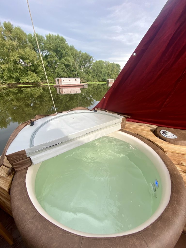 touespa9 Hébergement insolite en Auvergne : un bateau avec jacuzzi sur leau paisible.